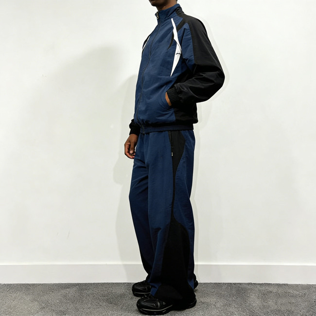 ʻIke ʻaoʻao o ke kanaka e ʻaʻahu ana i kahi ʻaʻahu pale makani me kekahi lima i hoʻokomo ʻia i loko o ka ʻeke o kahi ʻaʻahu