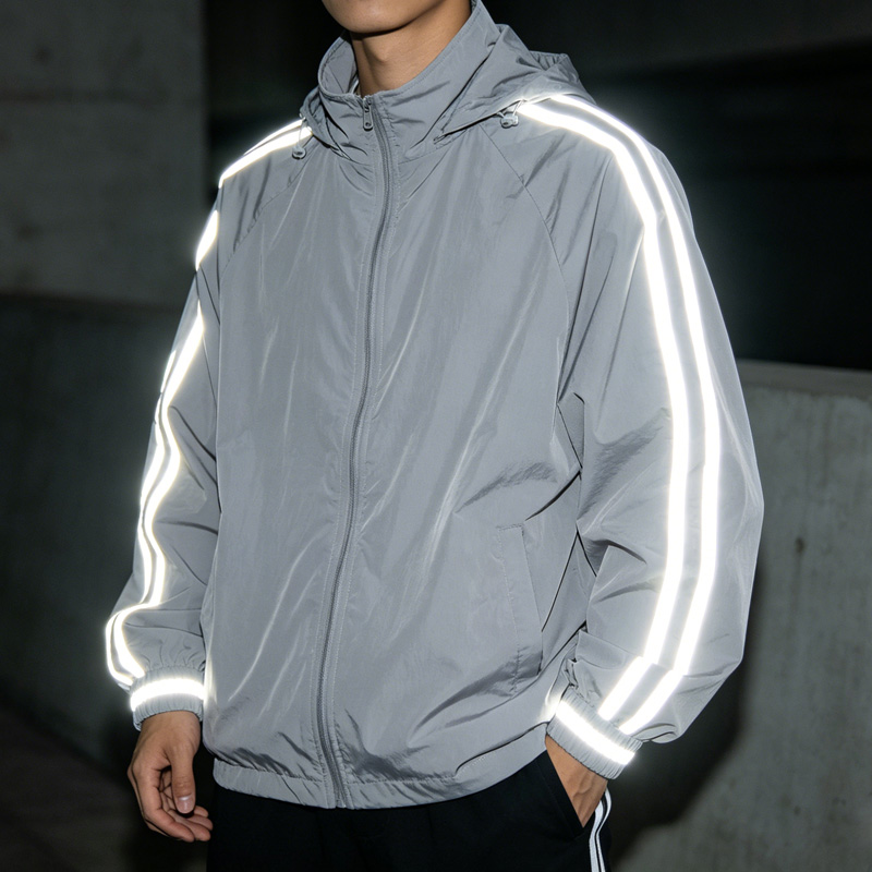 পুরুষদের ধূসর রঙের প্রতিফলক উইন্ডব্রেকার জ্যাকেট, প্রতিফলক স্ট্রাইপযুক্ত হুডওয়ালা স্ট্রিটওয়্যারের সম্মুখ দৃশ্য, রাতে দৃশ্যমানতা।