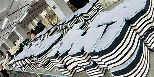 Stacked garment fabric pieces prepared for bulk cutting in activewear production.