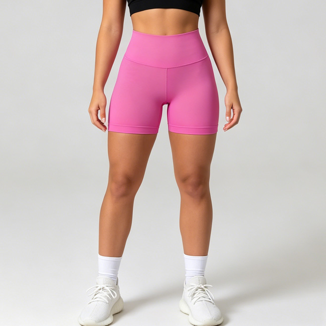 Woman standing with both legs apart, wearing hot pink high waisted fitted shorts with white sneakers.