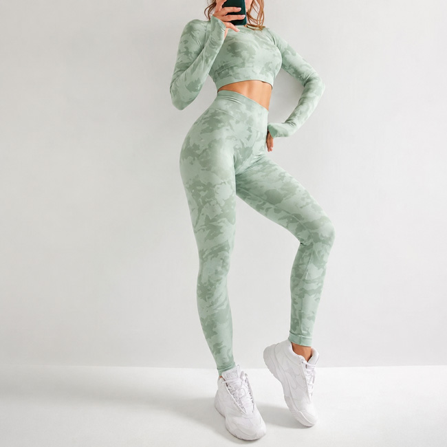 Woman posing with one hand on her waist and one knee lifted, wearing a sage green marble print crop top and matching leggings set.