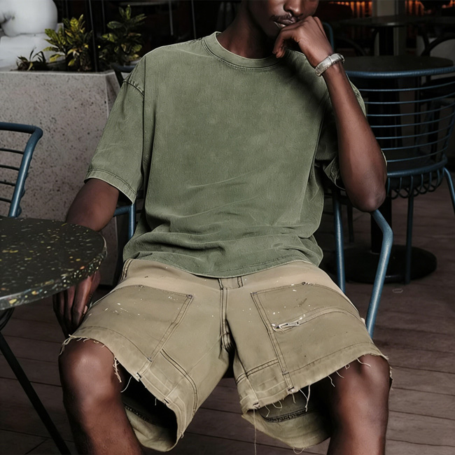 A model wearing a crew neck t shirt sits on a chair