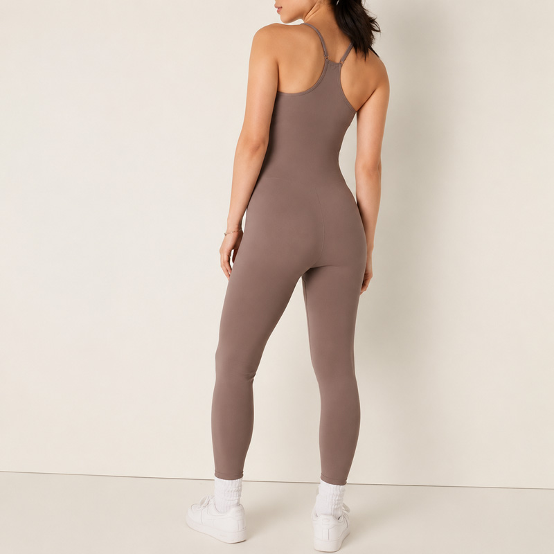 Back angle view of a woman turning slightly to the side while wearing a taupe sleeveless full-length unitard.