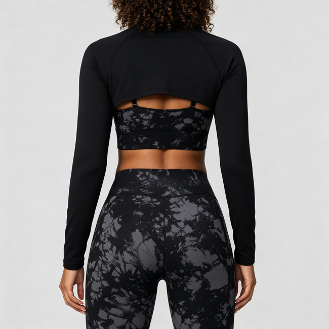 Back view of a woman standing naturally while wearing a black marble print long sleeve 3-piece workout set with a cutout back detail.