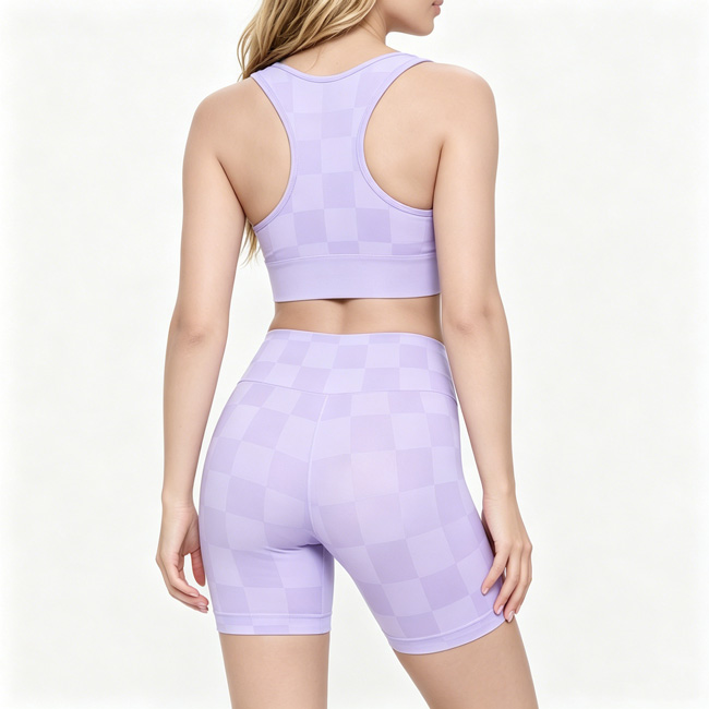Back view of a woman standing naturally while wearing a lavender checkered racerback sports bra and matching shorts set.