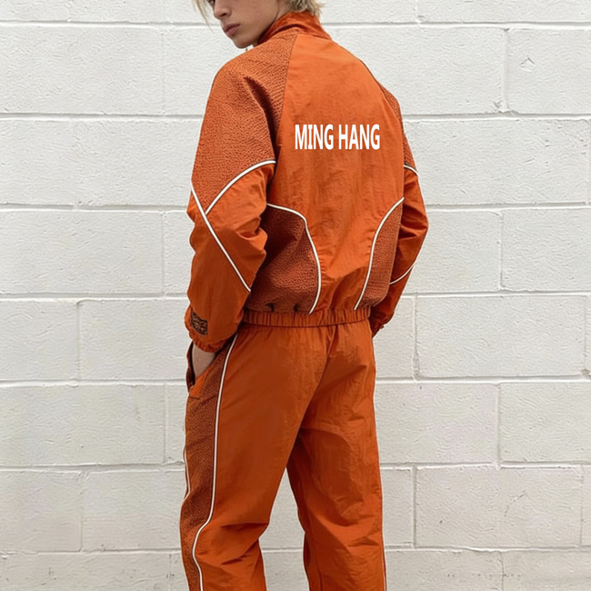 A man wearing a color block windbreaker set with both hands inserted into his pants pockets, side view