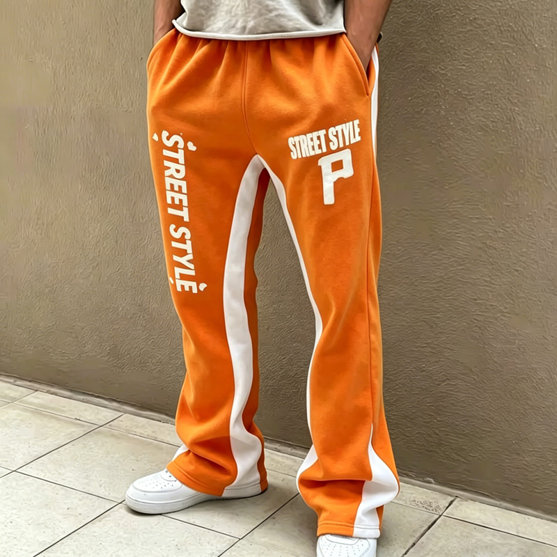 close-up of men's orange sweatpants with "Street Style" print and white side stripes, hip hop style